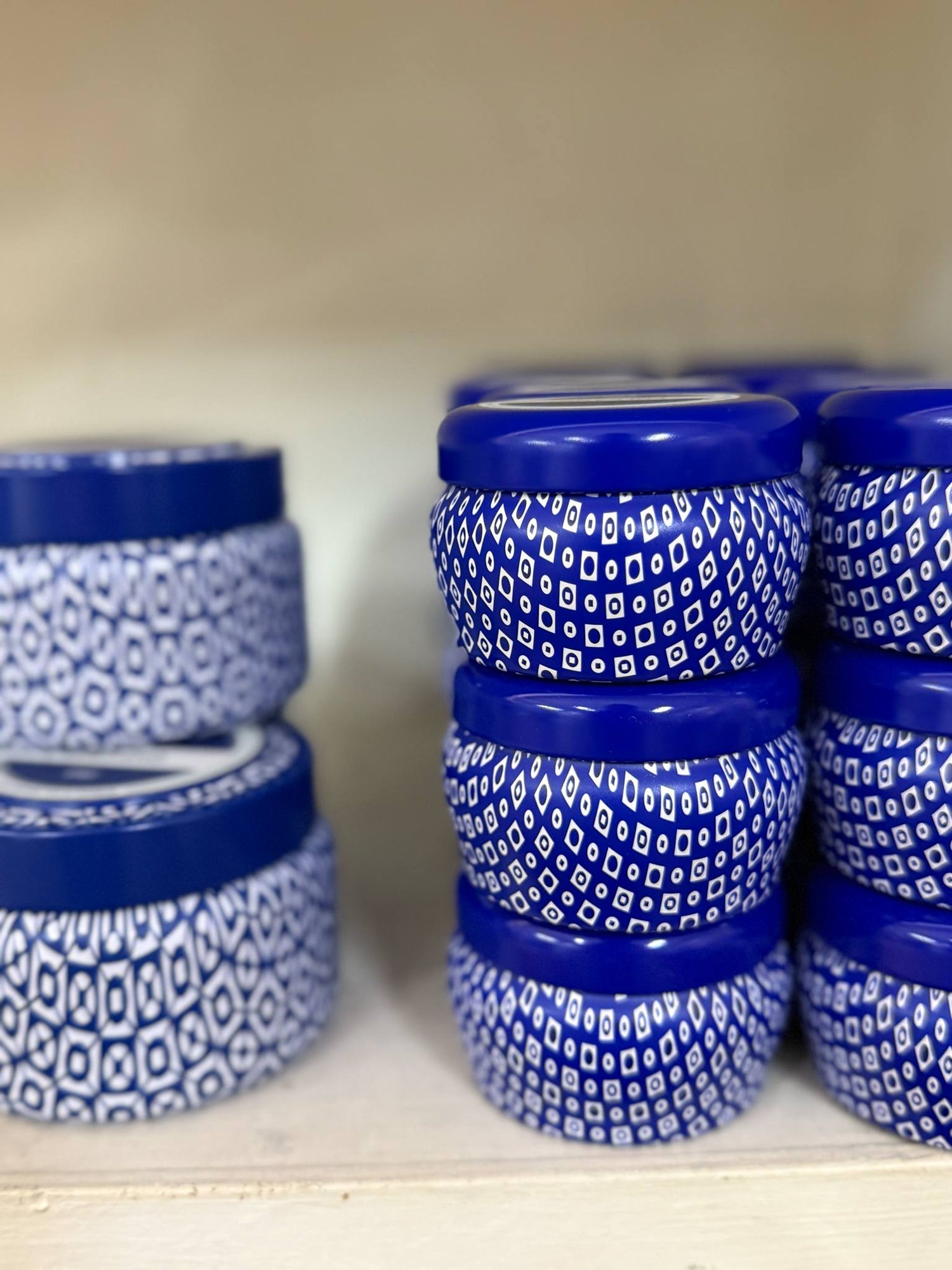 Smiling woman holding a large bundle of Capri Blue Volcano products including candles, diffusers, sprays, and lotions in vibrant blue and white packaging.